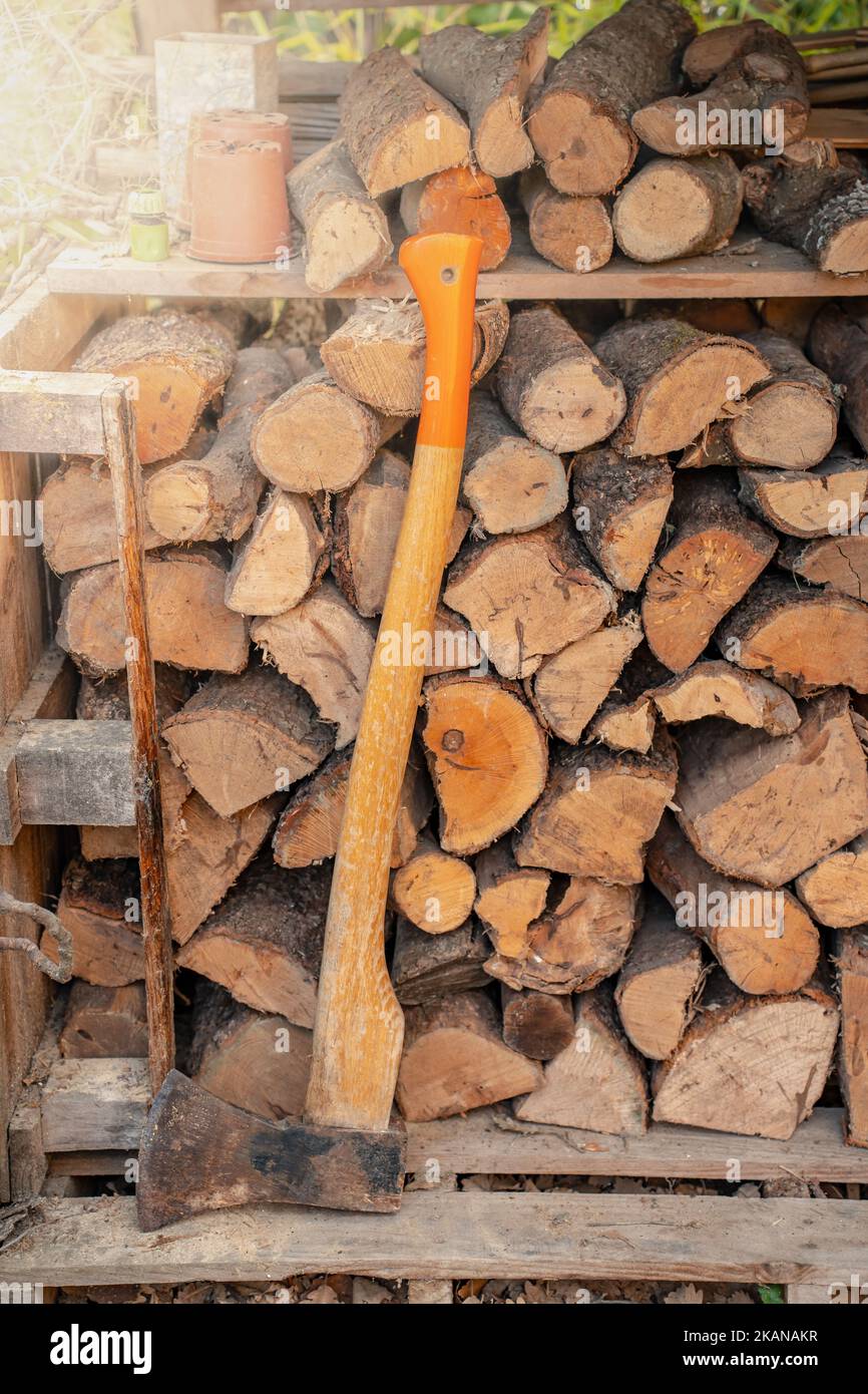 Axt vor einem Holzstapel in einem Holzschuppen. Natürlicher Hintergrund. Stockfoto