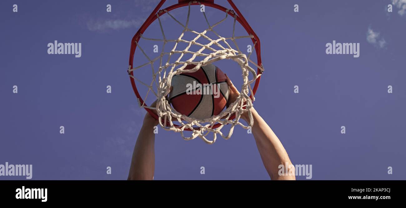dunk im Korb. slam Dunk in Bewegung. Sommer-Aktivität. Lächelnder Mann mit Basketball-Ball. Horizontales Posterdesign. Web-Banner-Header, Kopierbereich. Stockfoto