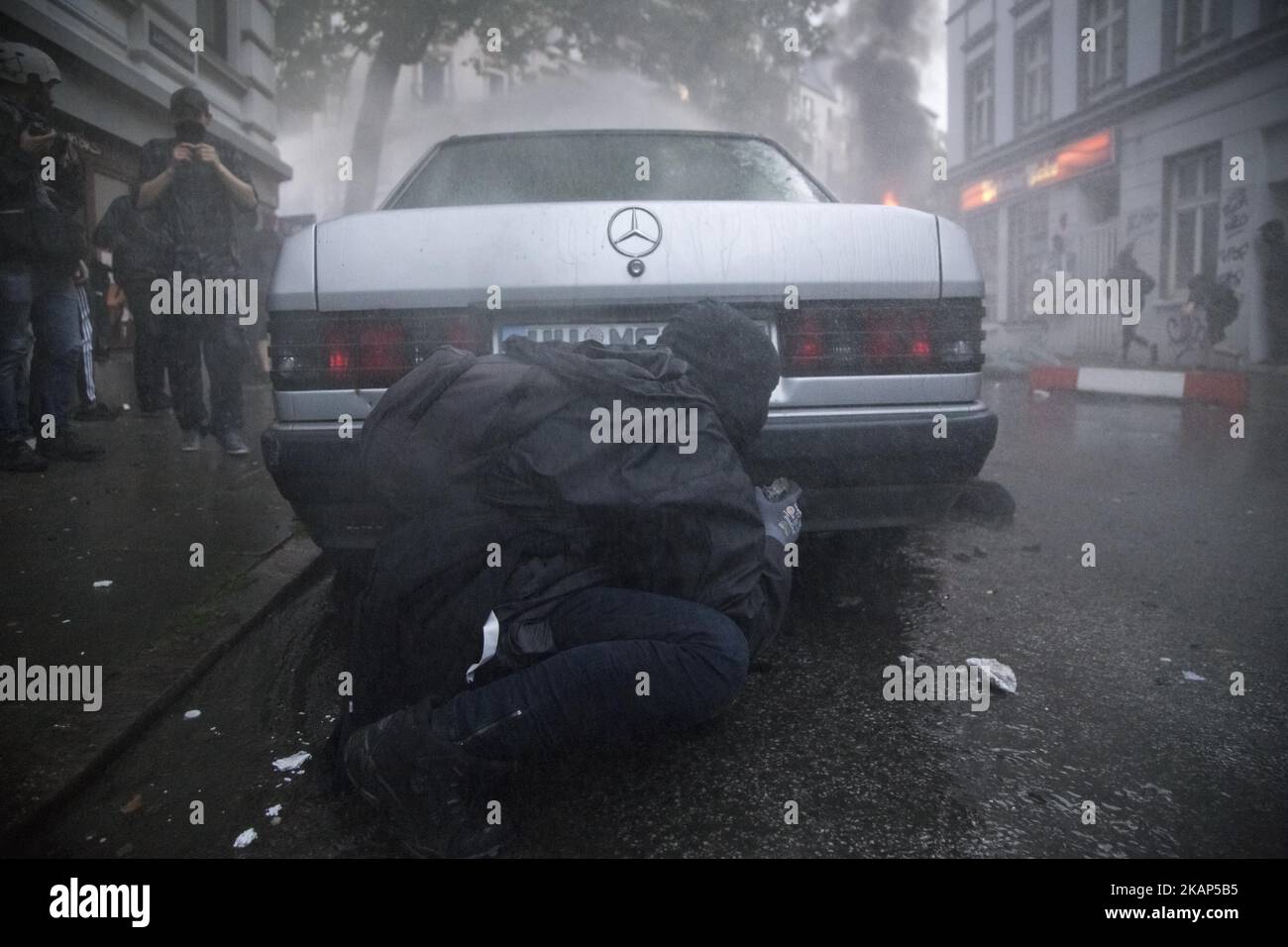 Während der Unruhen im Stadtteil St. Pauli während des G 20-Gipfels in Hamburg am 8. Juli 2017 versteckt sich ein Mann hinter einem Auto. Die Behörden sind auf große und disruptive Proteste vorbereitet, als die Führer der G20 Nationen zum Gipfel vom 7-8 G20. Juli in Hamburg eintreffen. Die Behörden sind auf große und disruptive Proteste vorbereitet, als die Führer der G20 Nationen zum Gipfel vom 7-8 G20. Juli in Hamburg eintreffen. (Foto von Maciej Luczniewski/NurPhoto) *** Bitte nutzen Sie die Gutschrift aus dem Kreditfeld *** Stockfoto