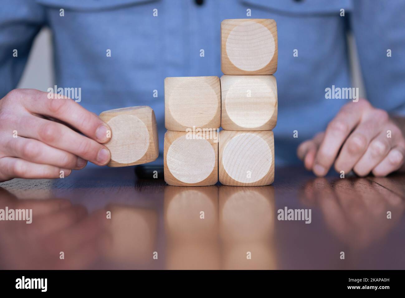 Nahaufnahme eines Geschäftsreisenden, der große Holzblöcke arrangiert. Geschäftsstrategie und -Lösungen Stockfoto