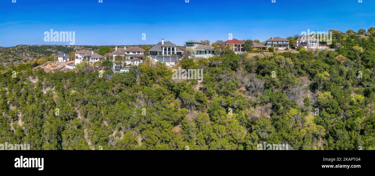 Austin, Texas - Berghochhäuser vor dem blauen Himmel. Villen auf einem Berg mit grünen Bäumen an seinem Hang vorne. Stockfoto