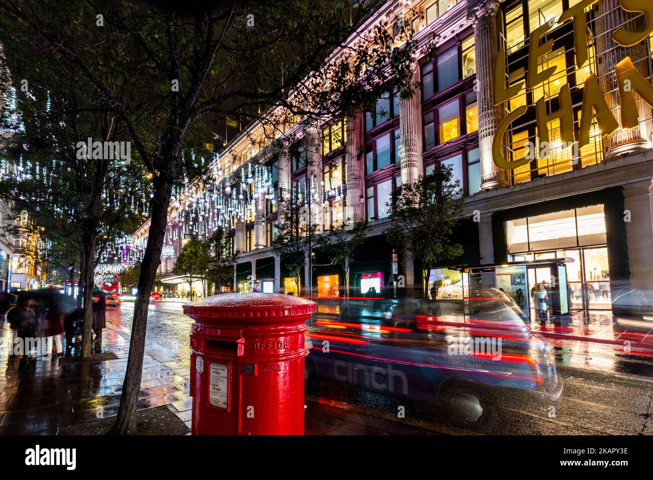 Weihnachten 2022, wenn die Lichter eingeschaltet werden mit Blick über die geschäftige oxford Street nach Selfridges.im Vordergrund ist ein roter Briefkasten und ein Taxi. Stockfoto