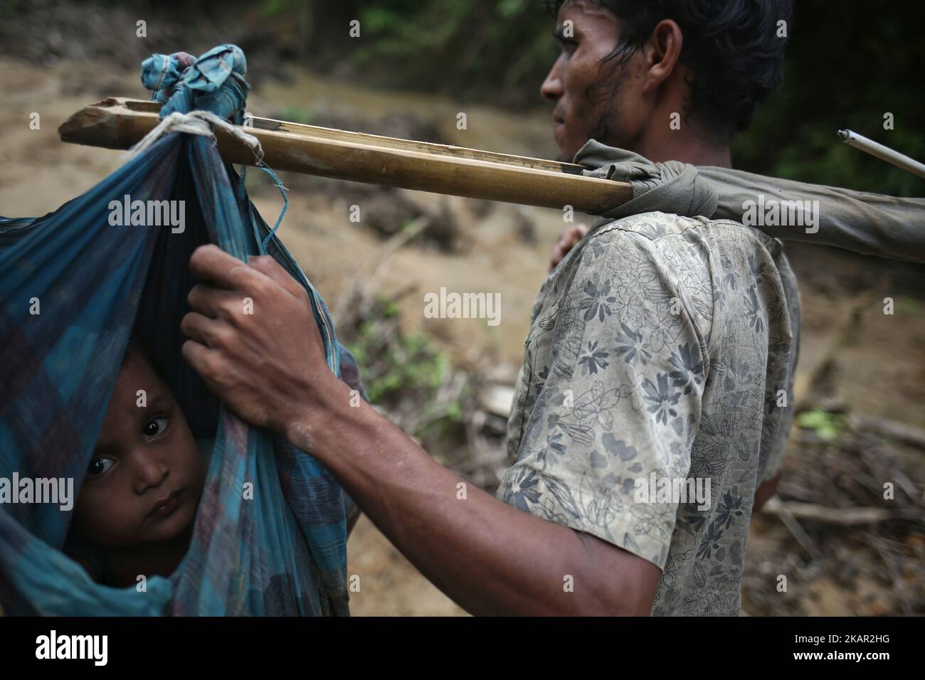 Ein Rohingya-Kind wird auf einer Schlinge getragen, während seine Familie nach dem Überqueren der Grenze nach Bangladesch in der Nähe von Cox's Bazar's Teknaf-Gebiet durch den Hügel geht, Dienstag, 5. September 2017 Insgesamt 87.000 überwiegend Rohingya-Flüchtlinge sind seit dem Ausbruch der Gewalt im benachbarten Myanmar am 25. August in Bangladesch angekommen. Die Vereinten Nationen sagten heute, inmitten der wachsenden internationalen Kritik an Aung San Suu Kyi. Rund 20.000 weitere wurden an der Grenze in Erwartung der Einreise massiert, teilte die UNO in einem Bericht mit. (Foto von Mushfiqul Alam/NurPhoto) Stockfoto