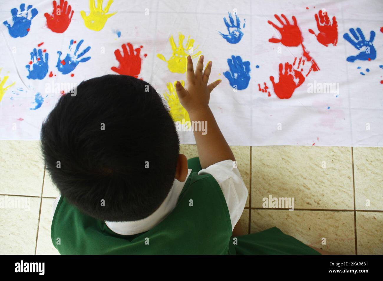 At-Taqwa-Kindergartenstudenten legen in Jakarta, 11. September 2017, ihre Handdrucke mit bunten Aquarellen auf weiße Tücher. Die Handdrucke, die sie geben, sind eine Form der Solidarität und sie sammeln Spenden für Kinder aus Myanmar, die in einem ethnischen Konflikt im Bundesstaat Rakhine in Myanmar unter Gewalt leiden. Die von der indonesischen Kinderschutzeinrichtung initiierte Bewegung zielt darauf ab, 10.000 Handschellen indonesischer Kinder zu erhalten, die an UN-Vertreter in Jakarta übergeben werden, um die UN zu bitten, unverzüglich zu handeln, um Frieden in Myanmar zu schaffen. (Foto von Aditya Irawan/NurPhoto) Stockfoto