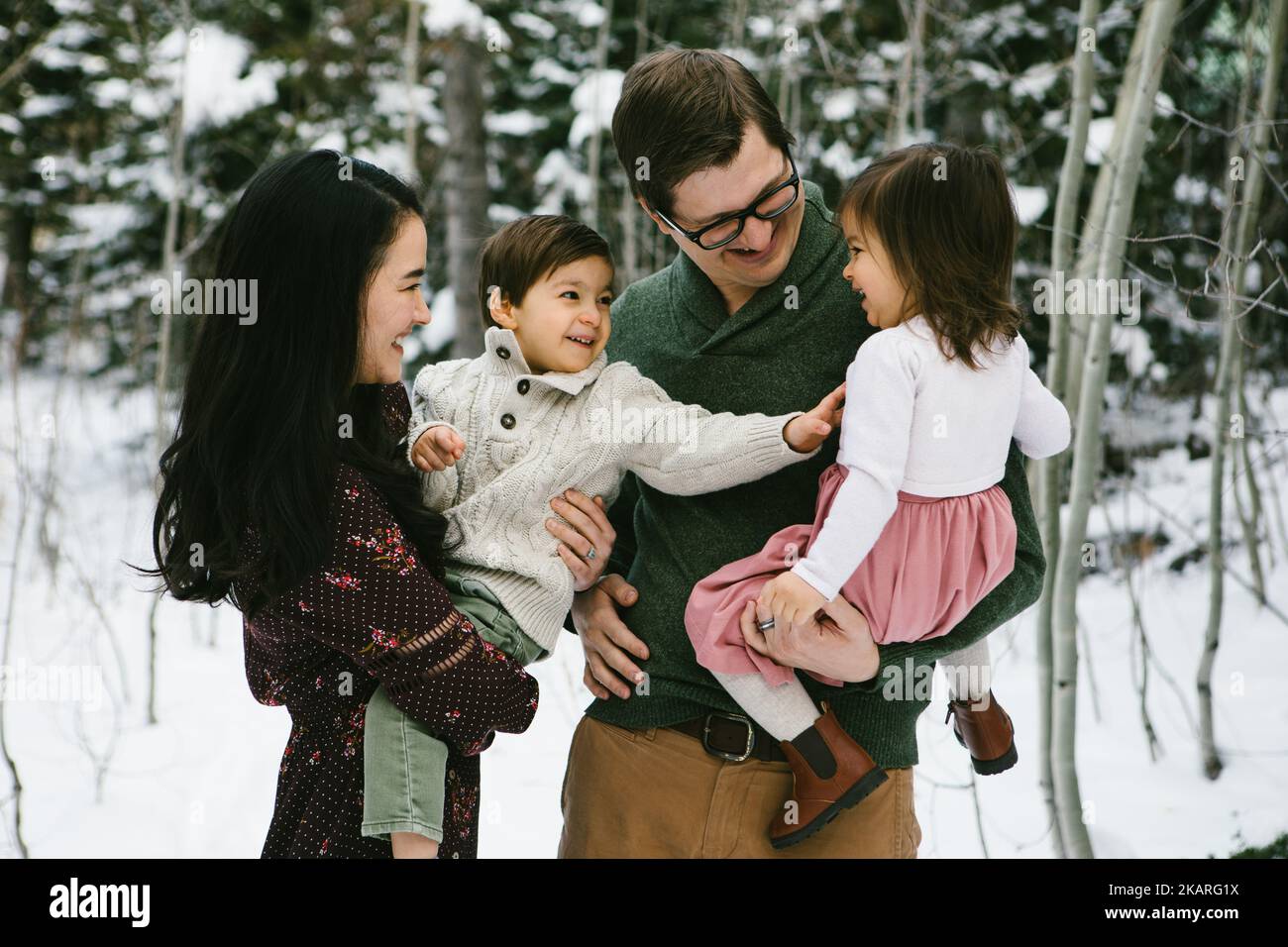 Multirassische Familie lacht und kitzelt in verschneiten Einheimischen Stockfoto