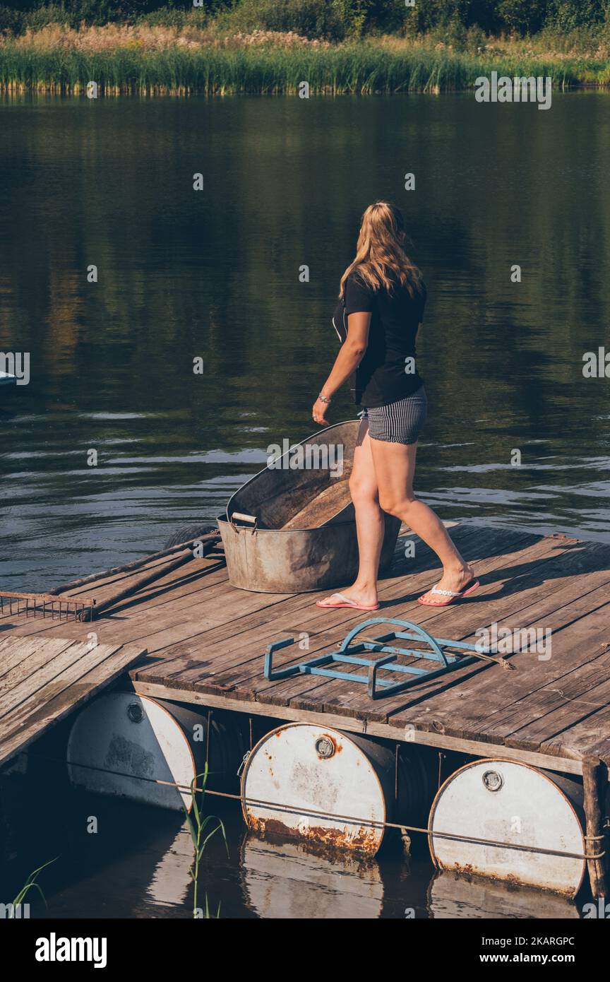 Frau, die auf einer alten Holzbrücke geht und über das Wasser zurückblickt Stockfoto