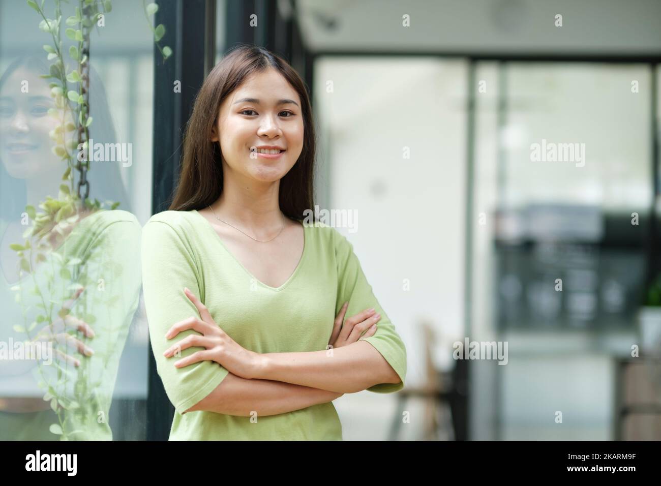 Porträt einer selbstbewussten Frau, die die Arme überkreuzt und die Kamera anlächelt. Stockfoto