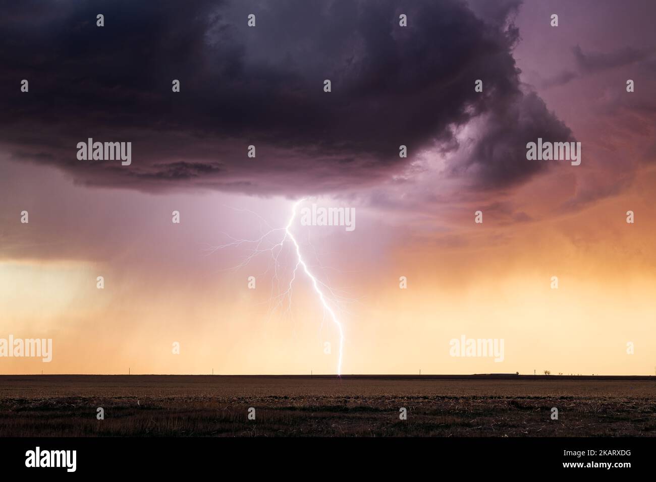 Ein starker Blitz trifft bei Sonnenuntergang in der Nähe von Lamar, Colorado, bei einem Gewitter ein Stockfoto
