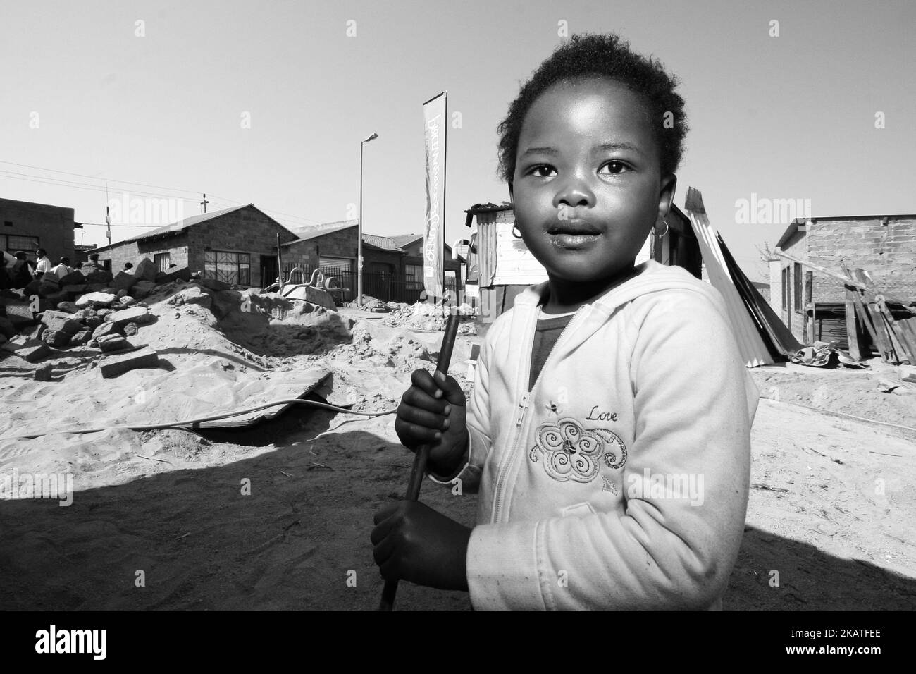 Ein kleines afrikanisches Mädchen, das auf der Baustelle im Hinterhof in einer Gemeinde in Soweto spielt Stockfoto
