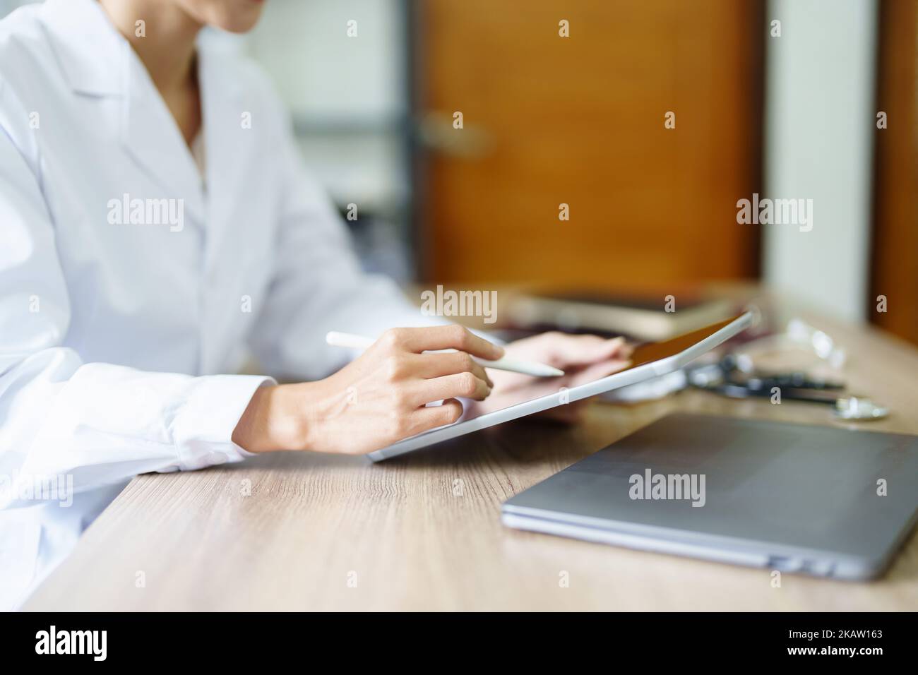 Eine asiatische Ärztin verwendet einen Tablet-Computer, um die Symptome des Patienten vor der Behandlung zu analysieren Stockfoto