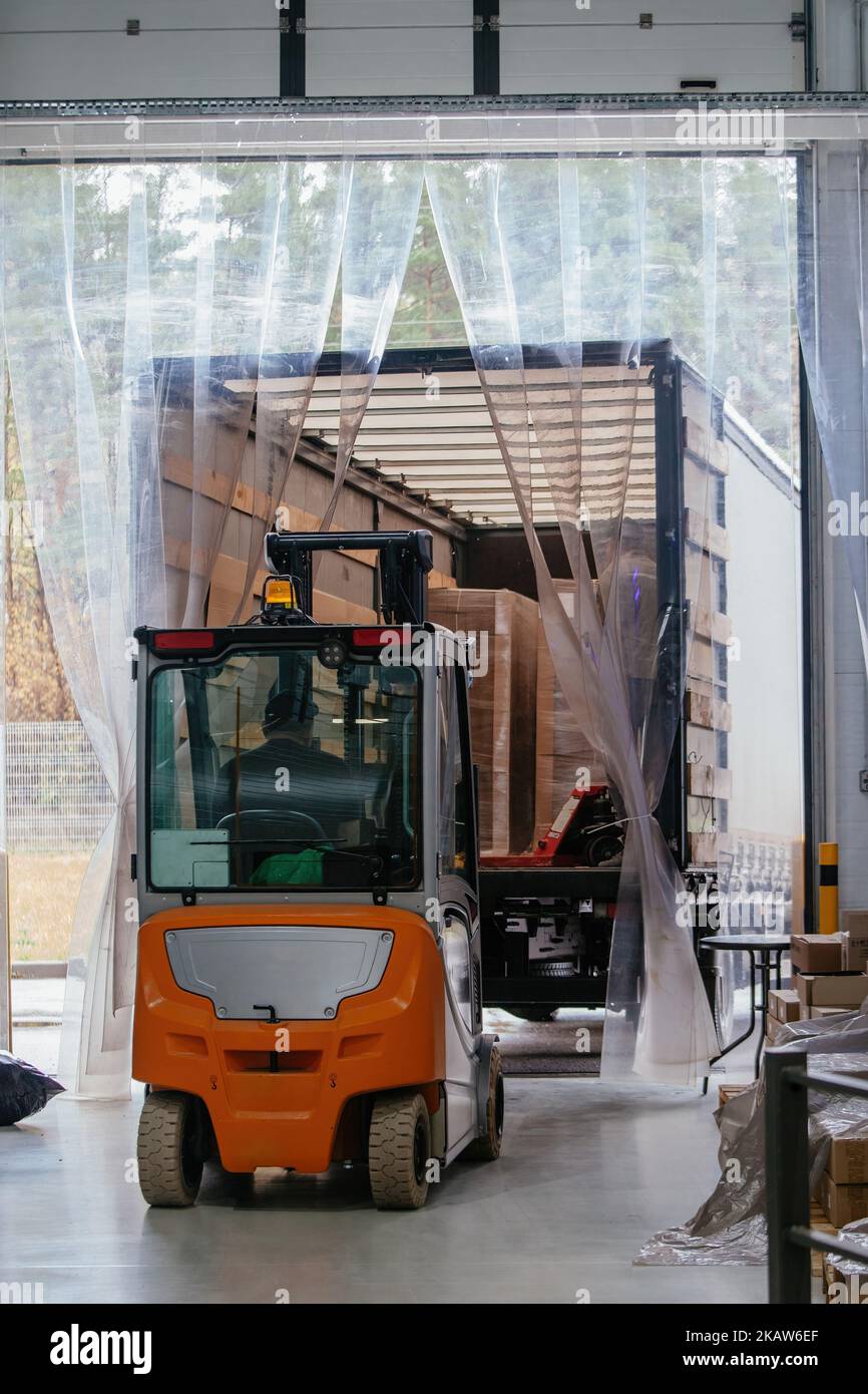 Der Gabelstaplerlader entlädt Ladung vom LKW Stockfoto