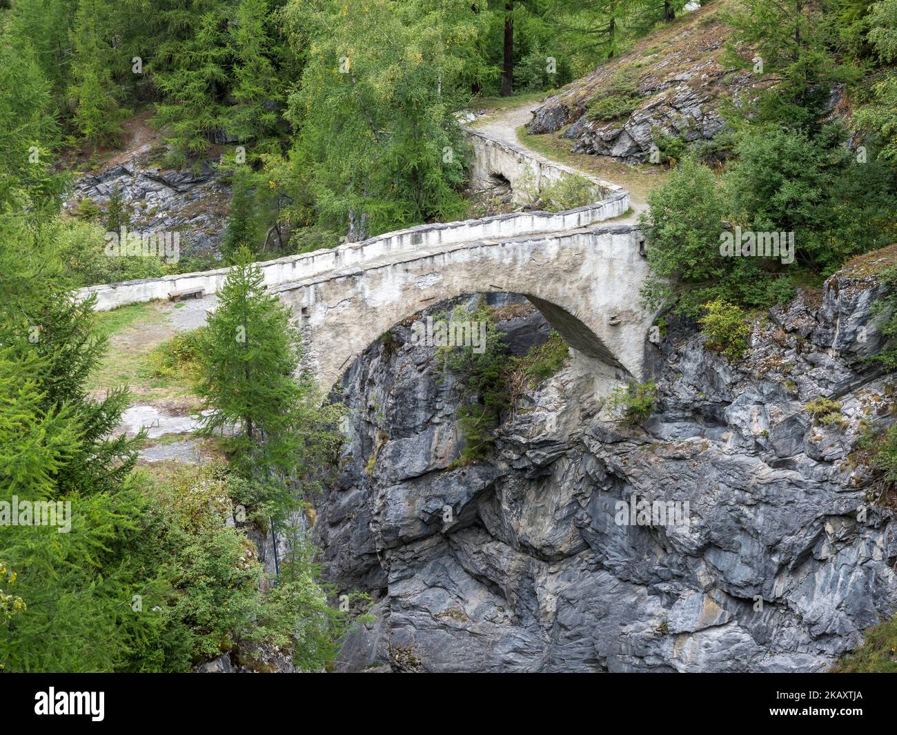 Historische Brücke über eine enge Schlucht direkt unterhalb des Staudamms Barrage de Mauvoisin, Val de Bagnes, Schweiz. Stockfoto