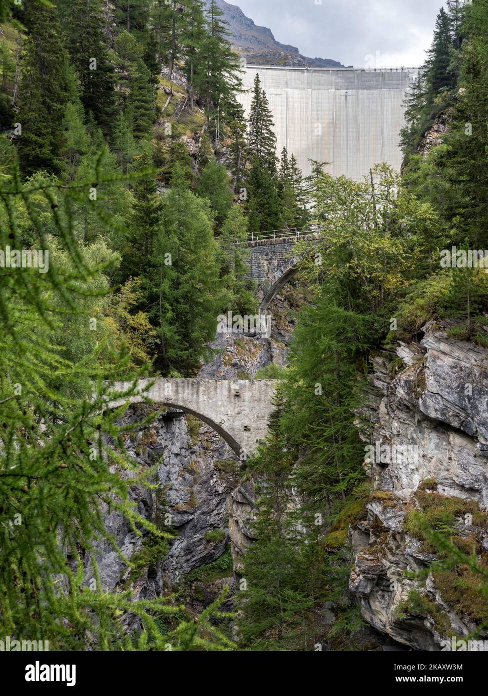 Historische Brücke über eine enge Schlucht direkt unterhalb des Staudamms Barrage de Mauvoisin, Val de Bagnes, Schweiz. Stockfoto