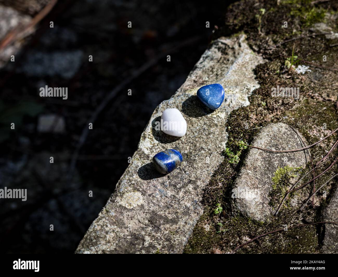 Eine Nahaufnahme eines Lapislazuli-blauen Kristalls auf einer moosigen Felsoberfläche unter der Sonne Stockfoto