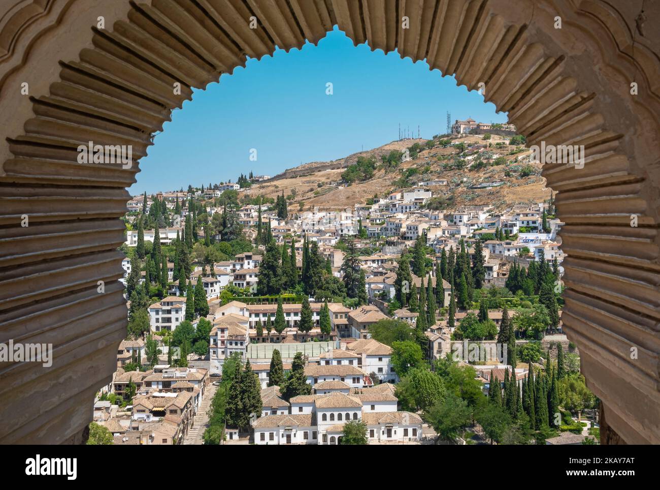 Vista de la ciudad de Granada através del arco de una ventana estilo árabe en la torre de las damas de la Alhambra, España Stockfoto Vista de la ciudad de Granada através del arco de una ventana estilo árabe en la torre de las damas de la Alhambra, España Stockfoto