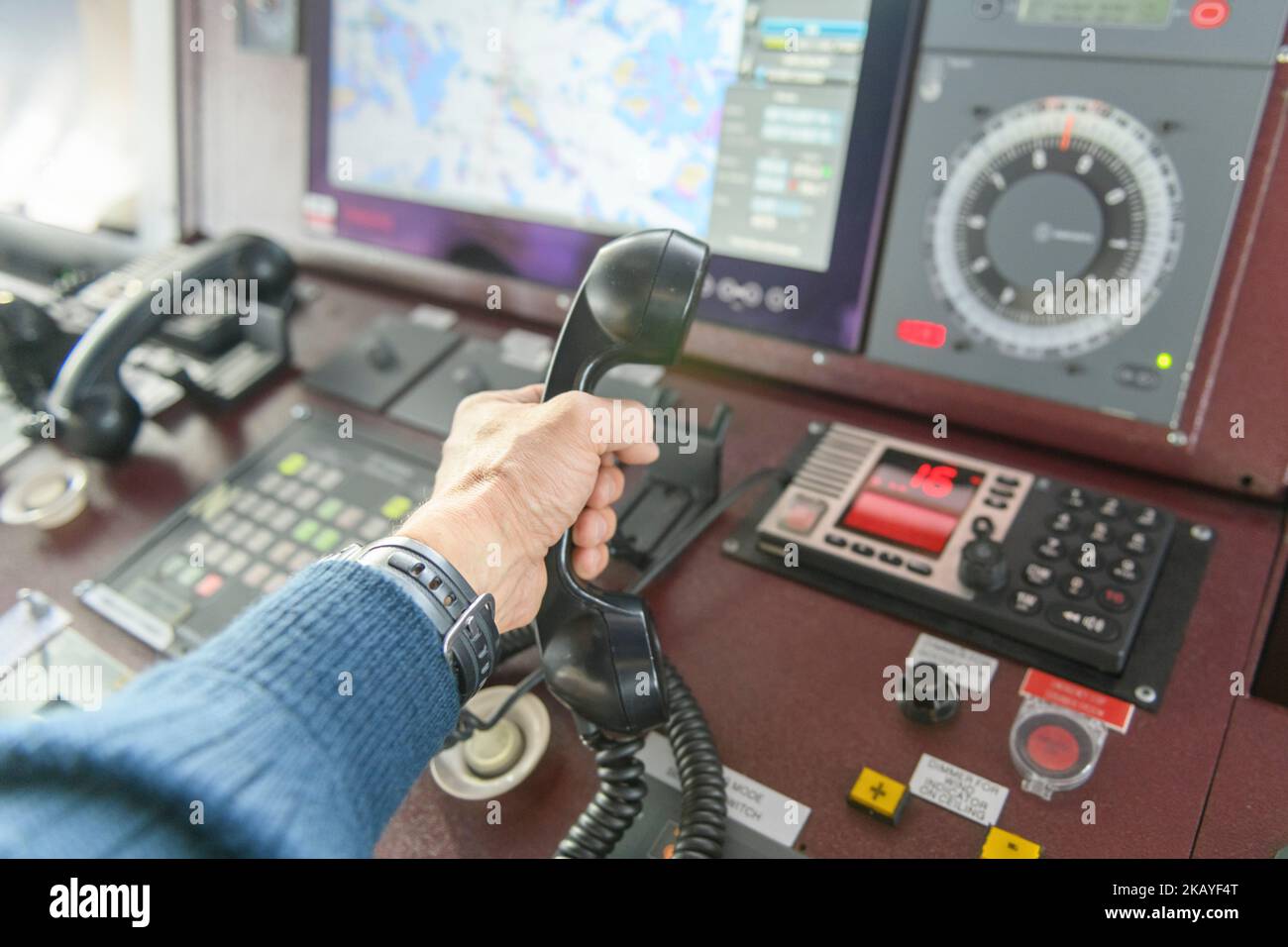 Navigationsbedienfeld und UKW-Funkgerät mit Hand. Funkkommunikation auf See. Arbeiten an der Schiffsbrücke. Stockfoto