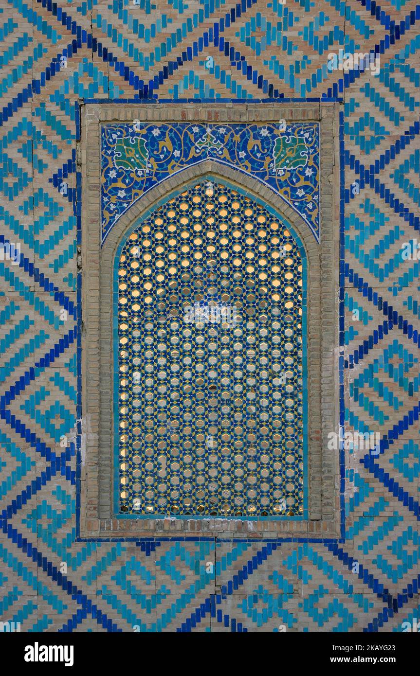 Nahaufnahme des Gitterfensters und des Mosaikdekors mit blauen Kacheln an der Wand von Sher Dor madrassa auf dem berühmten Registan-Platz in Samarkand, Usbekistan Stockfoto