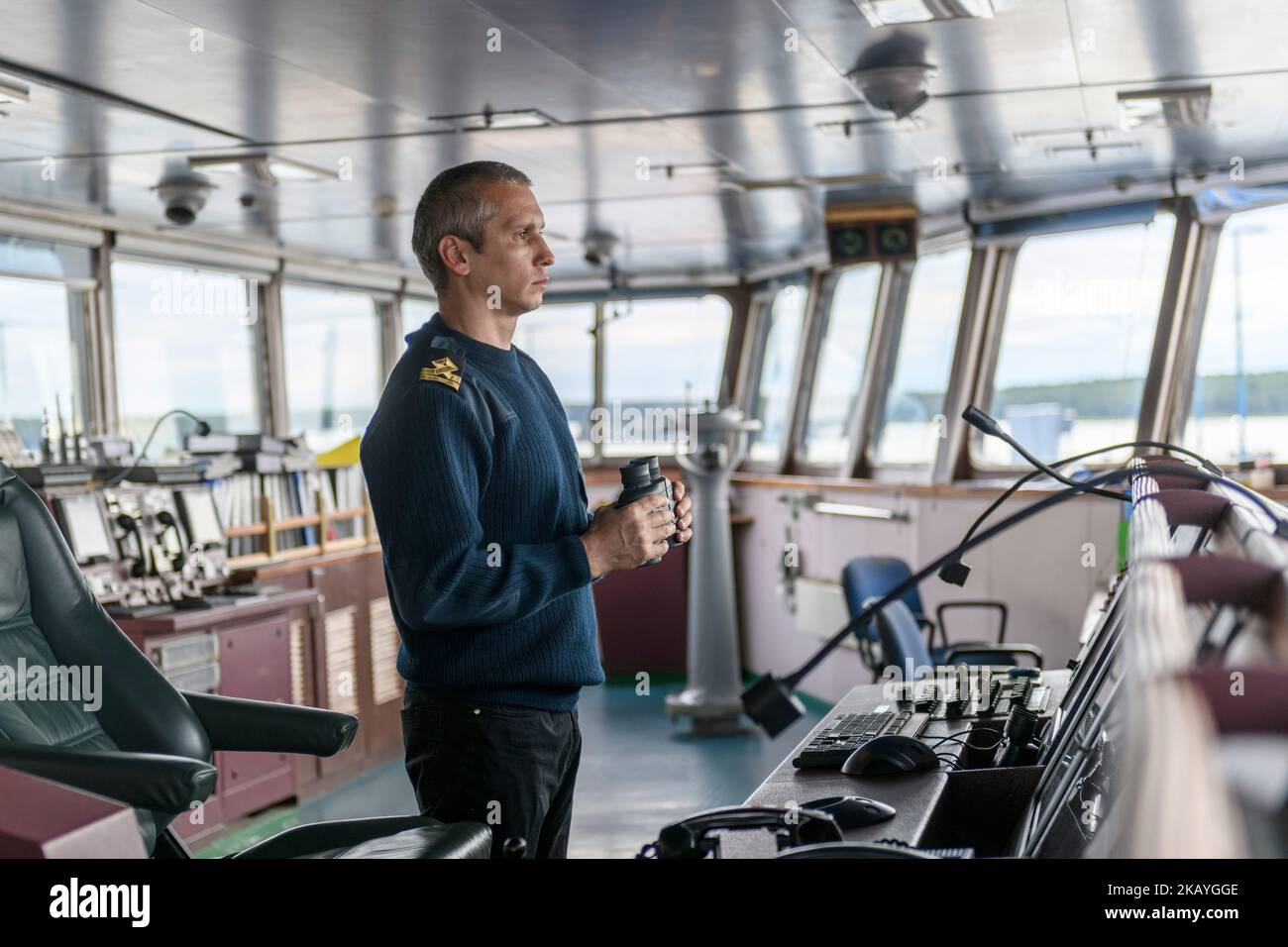 Deckoffizier mit Fernglas auf der Navigationsbrücke. Seemann an Bord des Schiffes. Gewerblicher Versand. Frachtschiff. Stockfoto