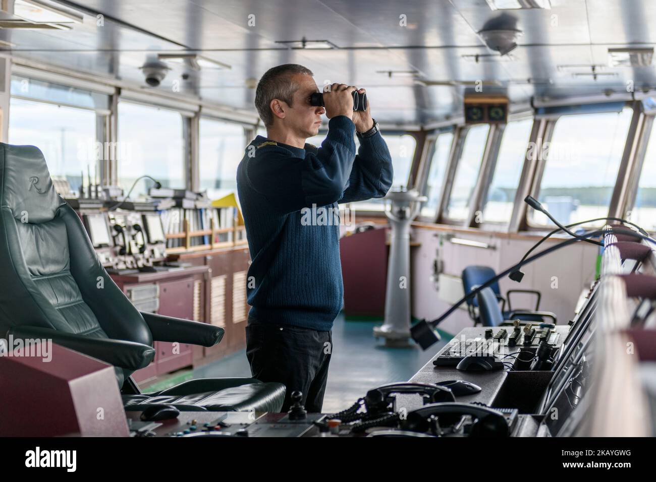 Deckoffizier mit Fernglas auf der Navigationsbrücke. Seemann an Bord des Schiffes. Gewerblicher Versand. Frachtschiff. Stockfoto