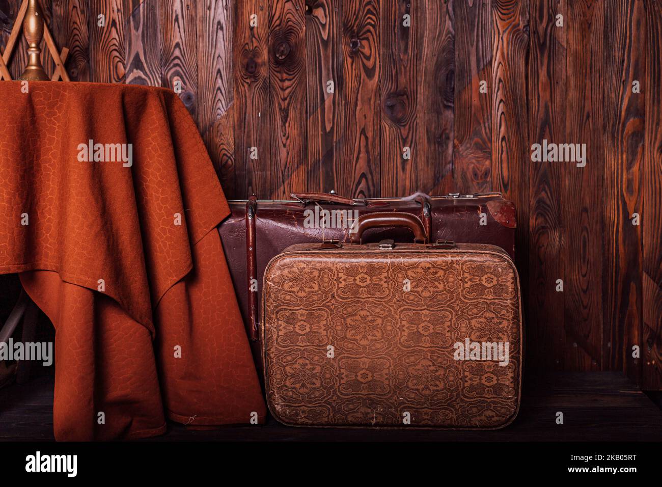 Alte Vintage-Koffer neben einem Tisch in der Nähe einer braunen Holzwand. Retro-Style Stockfoto