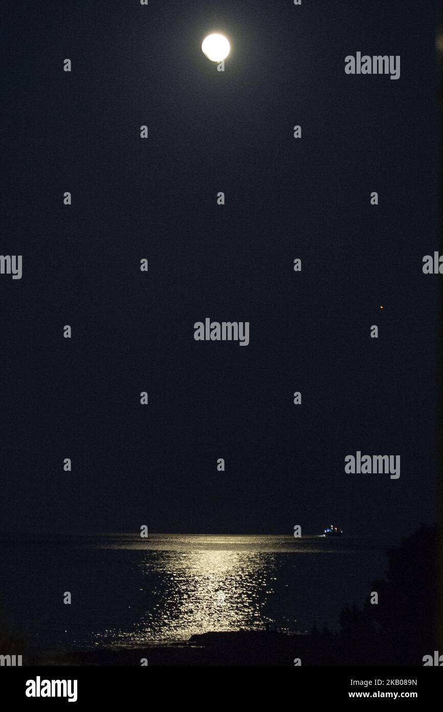 Der „Blutmond“ vor und während der Mondfinsternis im verwüsteten, aus dem Feuer stammenden Gebiet namens Mati in der Nähe von Athen. Das Schiff gehört der Küstenwache, da sie immer noch nach Menschen suchen. Die Finsternis ist die längste totale Mondfinsternis des Jahrhunderts, die einen Blutmond während eines Vollmondes zeigt 27. Juli 2018 - Mati, Attica - Griechenland (Foto von Nicolas Economou/NurPhoto) Stockfoto