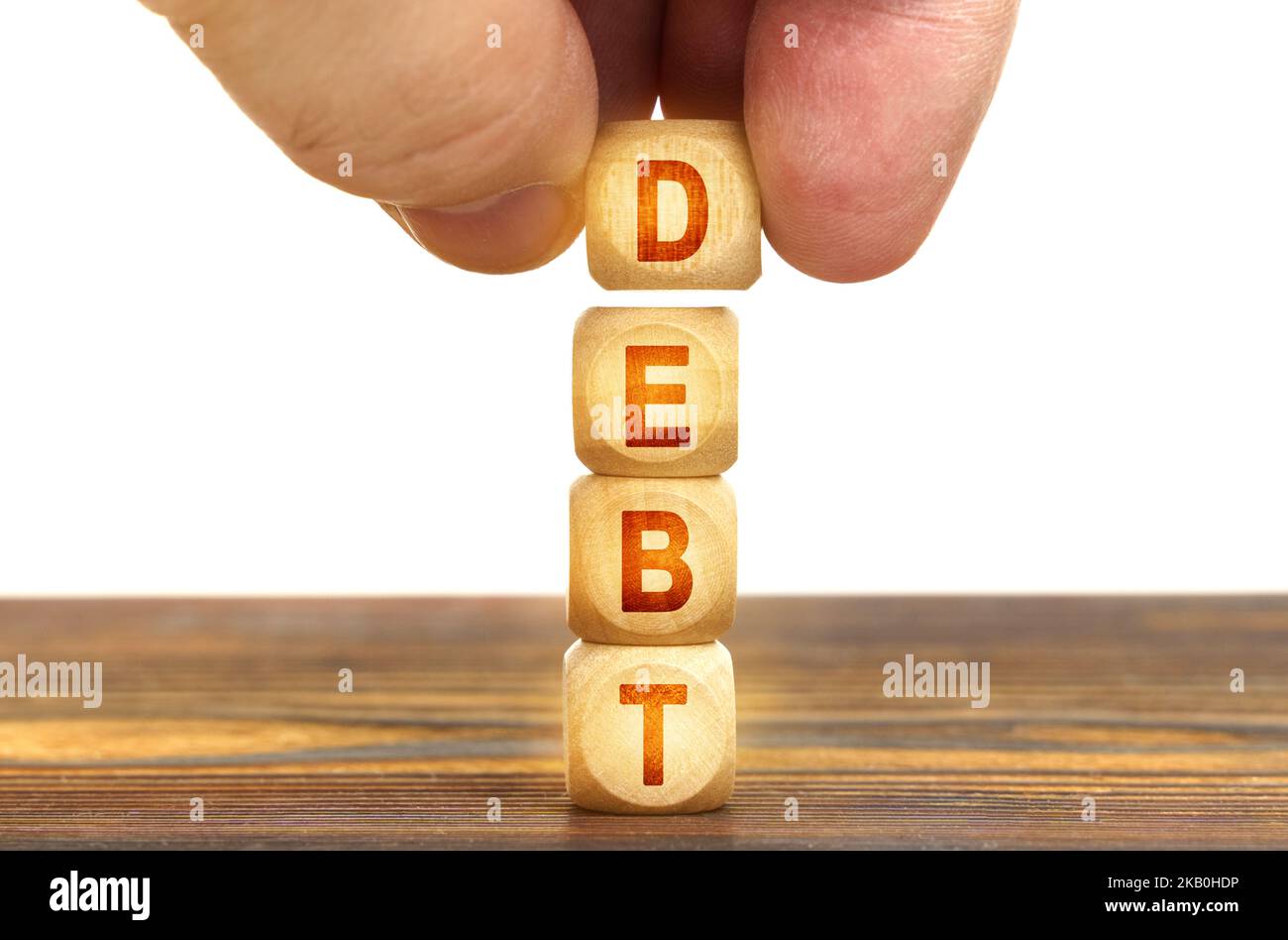 Geschäftskonzept. Ein Mann legt Holzwürfel mit der Aufschrift Schulden auf den Tisch Stockfoto