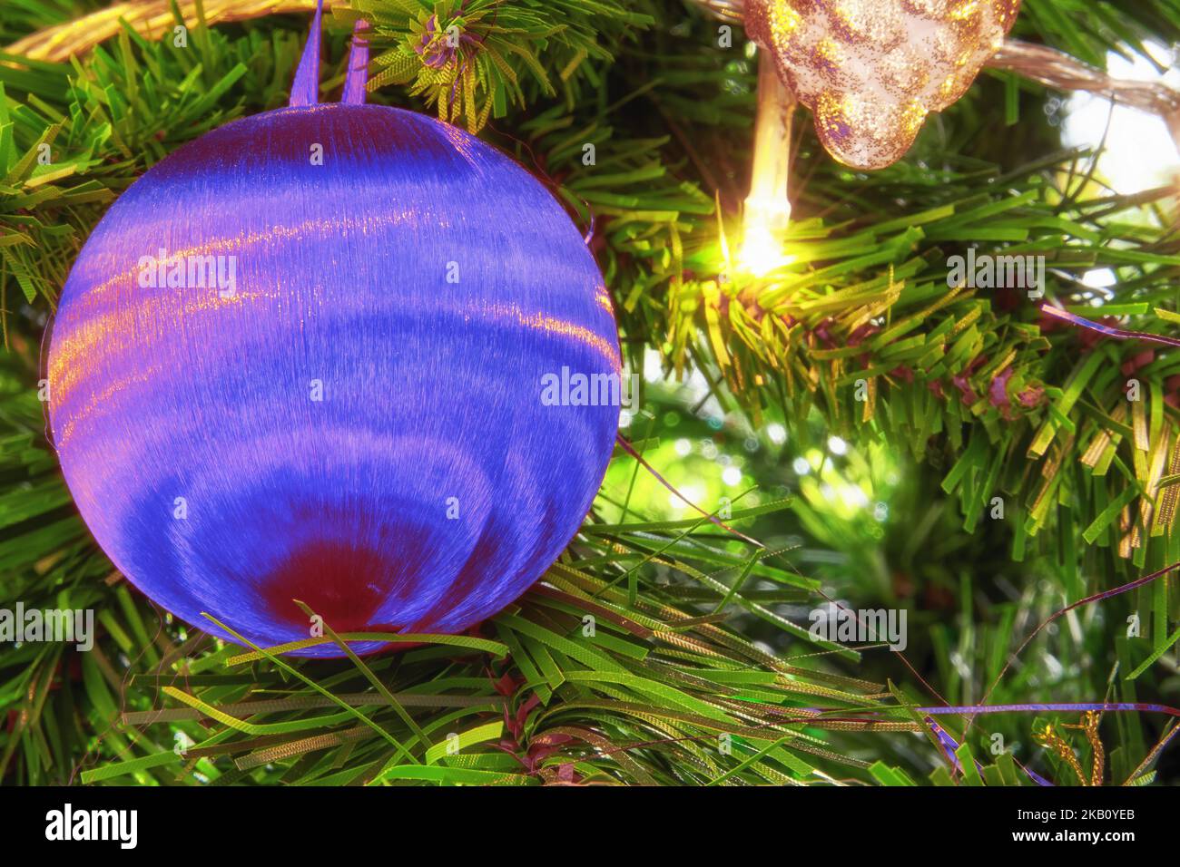 Leuchtend blaue Kugel auf dem immergrünen Christbaumzweig. Thema und Hintergründe des neuen Jahres Stockfoto