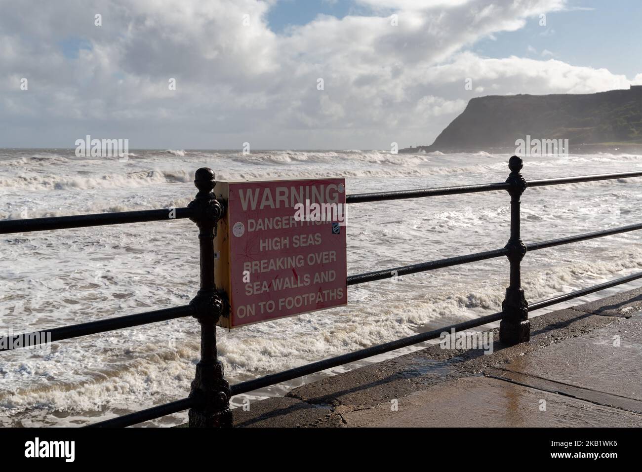 Scarborough, Großbritannien: Warnschild vor Gefahren durch hohe See, die bei Flut an der Küste der North Bay über Mauern und Fußwege brechen. Stockfoto