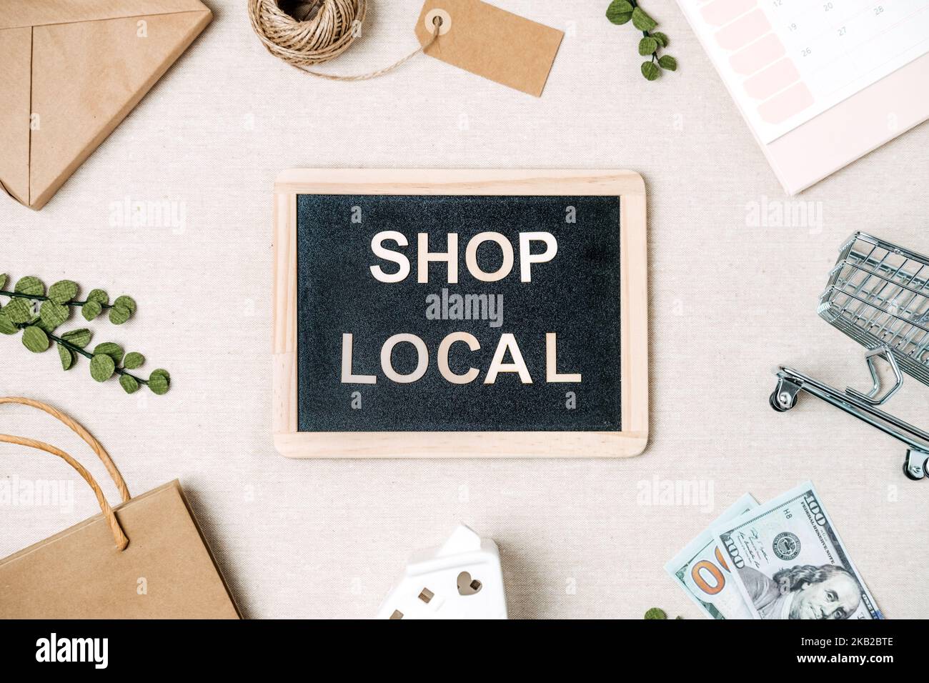 Shop lokaler Text auf Tafel geschrieben. Flat Lay mit Support Local Business Quote, Dekoration und Einkaufstasche, Geschenkboxen und Personal Stockfoto
