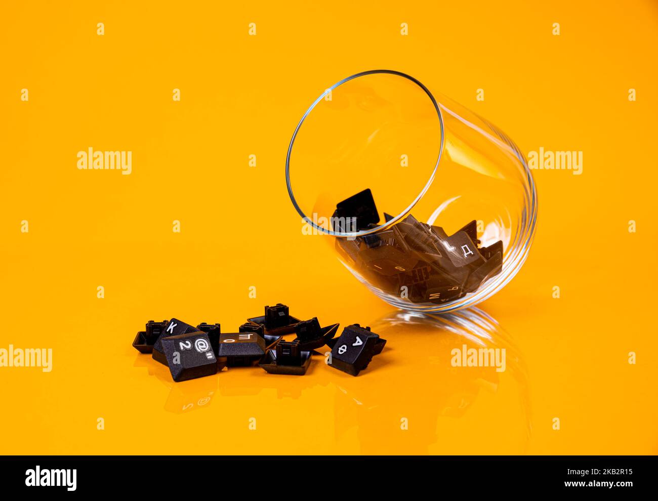 Tastatur-Taste in Glas in Eimer auf orangefarbenem Hintergrund isoliert Hacker Stockfoto