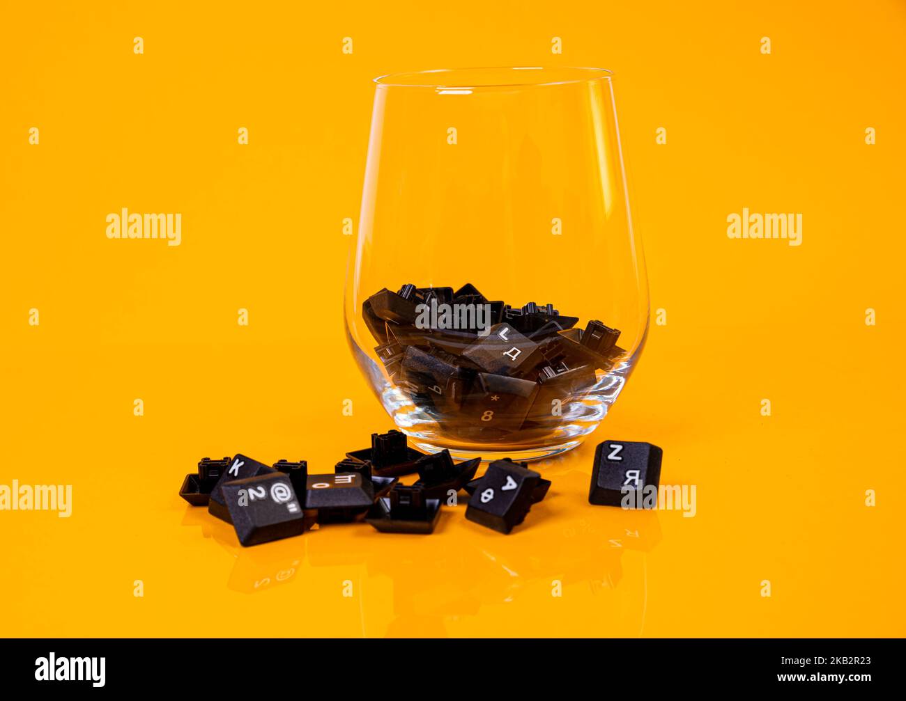 Tastatur-Taste in Glas in Eimer auf orangefarbenem Hintergrund isoliert Hacker Stockfoto