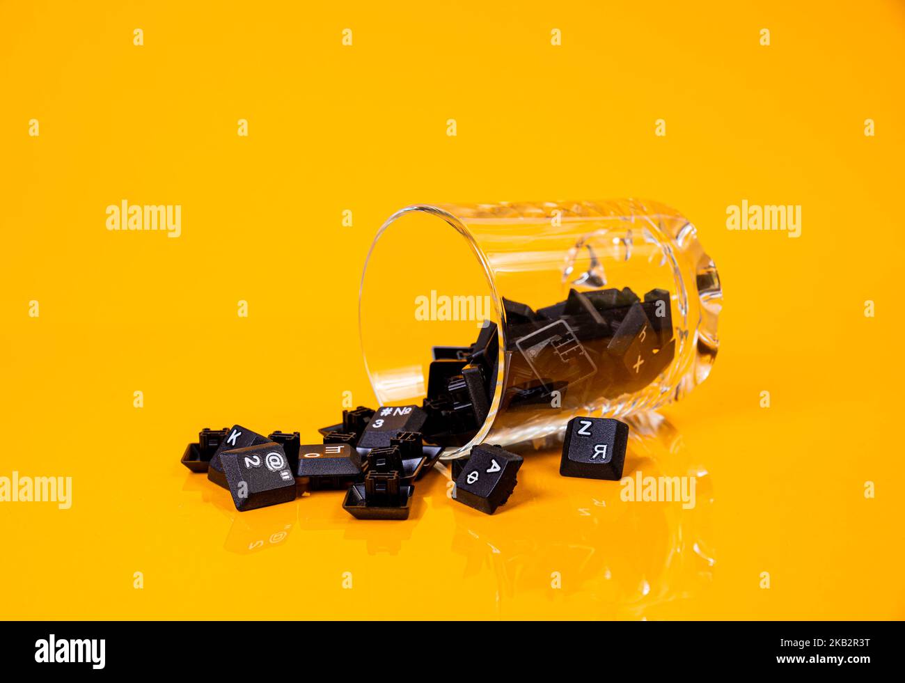 Tastatur-Taste in Glas in Eimer auf orangefarbenem Hintergrund isoliert Hacker Stockfoto