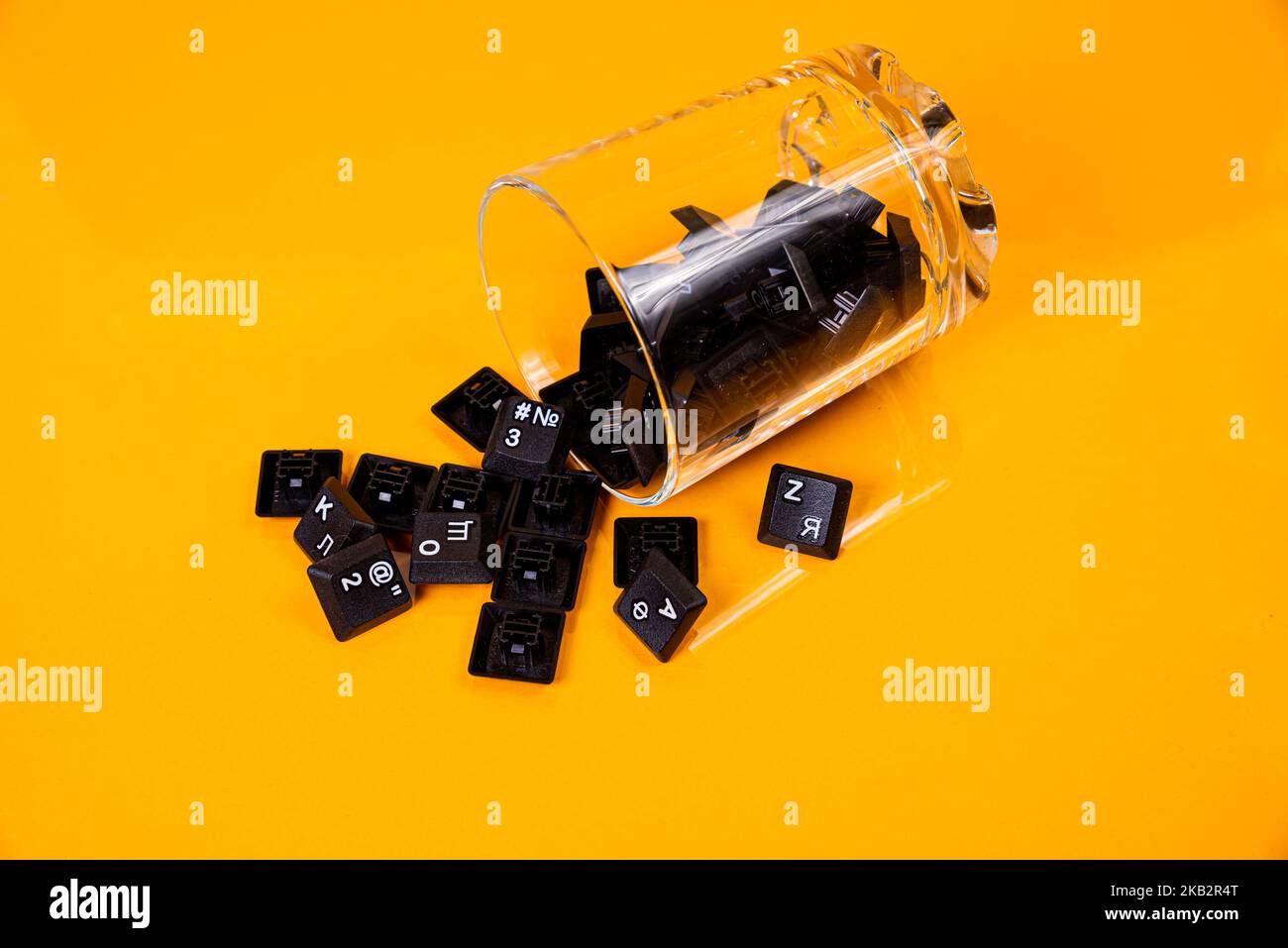 Tastatur-Taste in Glas in Eimer auf orangefarbenem Hintergrund isoliert Hacker Stockfoto