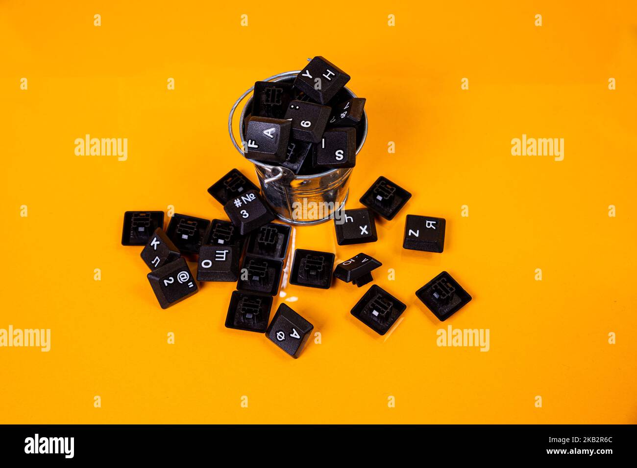 Tastatur-Taste in Glas in Eimer auf orangefarbenem Hintergrund isoliert Hacker Stockfoto