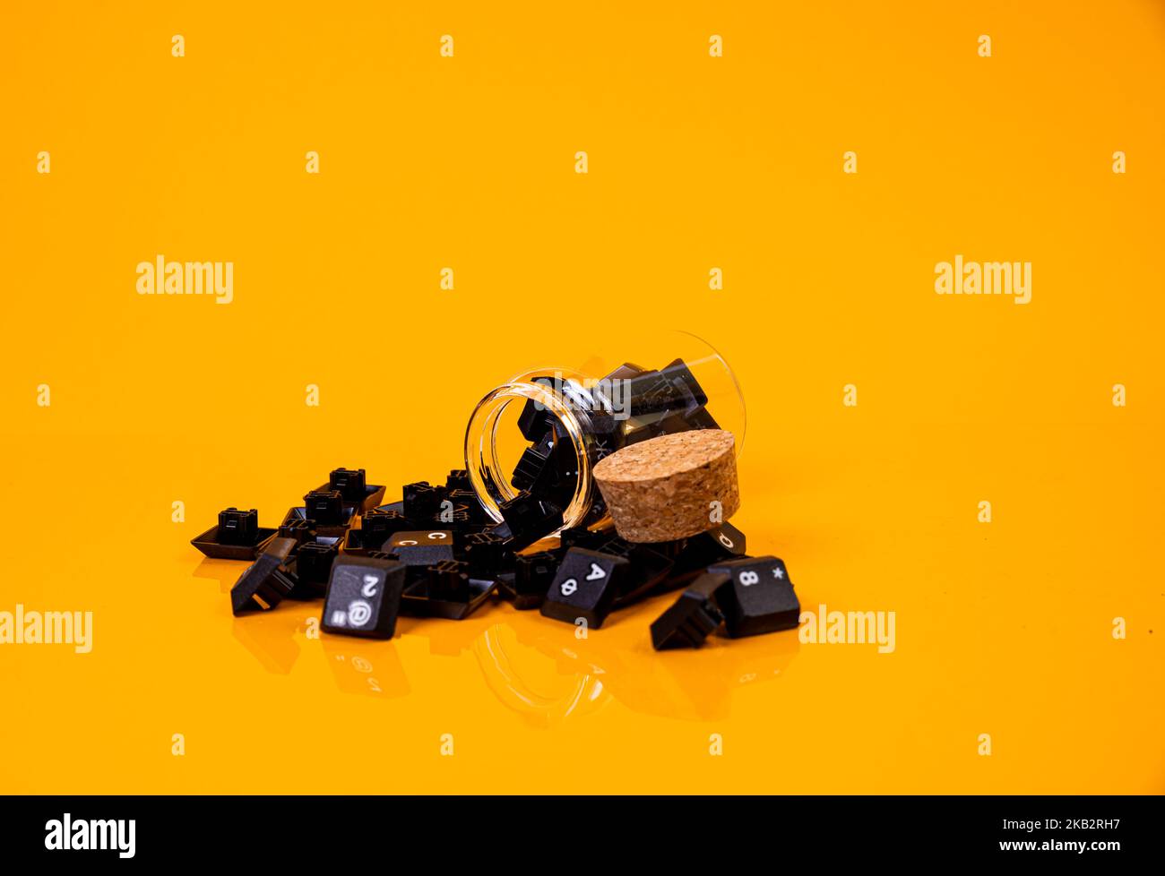 Tastatur-Taste in Glas in Eimer auf orangefarbenem Hintergrund isoliert Hacker Stockfoto