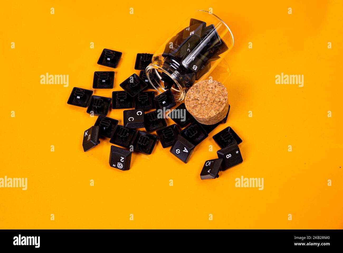 Tastatur-Taste in Glas in Eimer auf orangefarbenem Hintergrund isoliert Hacker Stockfoto