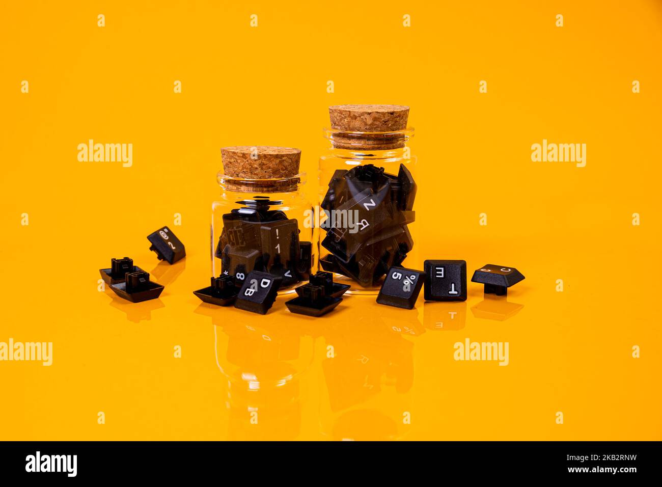 Tastatur-Taste in Glas in Eimer auf orangefarbenem Hintergrund isoliert Hacker Stockfoto