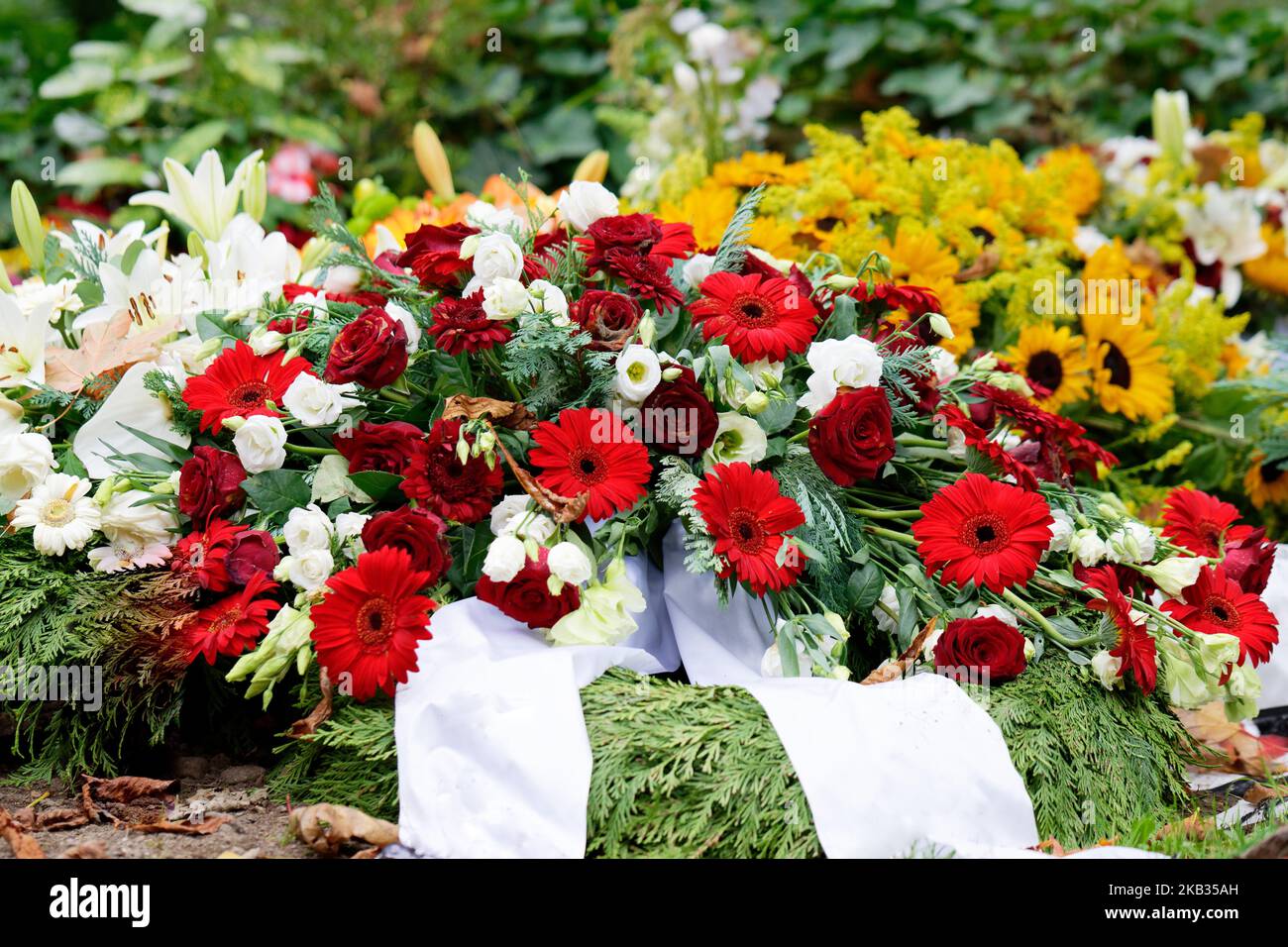 rosen, Gerbera, Lilien und Sonnenblumen auf einem Grab nach einer Beerdigung Stockfoto