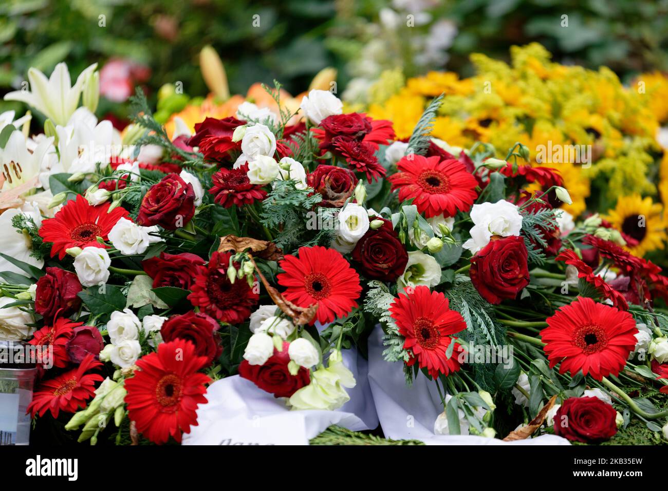 rosen, Gerbera, Lilien und Sonnenblumen auf einem Grab nach einer Beerdigung Stockfoto