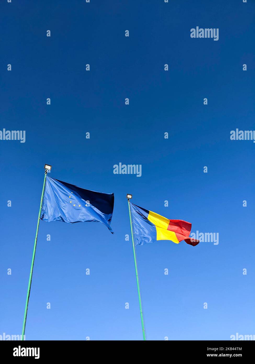 Flaggen Rumäniens und der Europäischen Union gegen den klaren blauen Himmel. Vertikal. Erstellen Sie ein Modell für den Kopierbereich Stockfoto