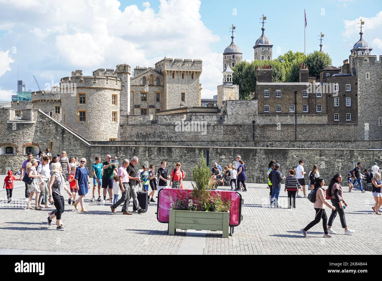 Touristen auf dem Tower Hill gehen entlang der Mauern des Tower of London, London England Großbritannien Stockfoto