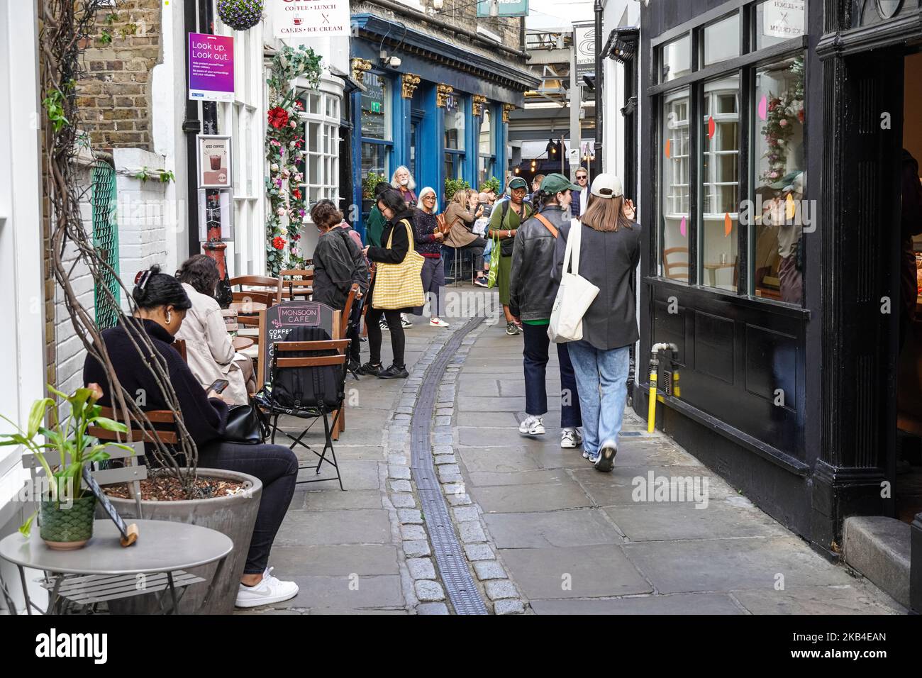 Touristen besuchen Geschäfte und Cafés auf der Turnpin Lane, eine enge Straße, die zum Greenwich Market, London England, Großbritannien führt Stockfoto