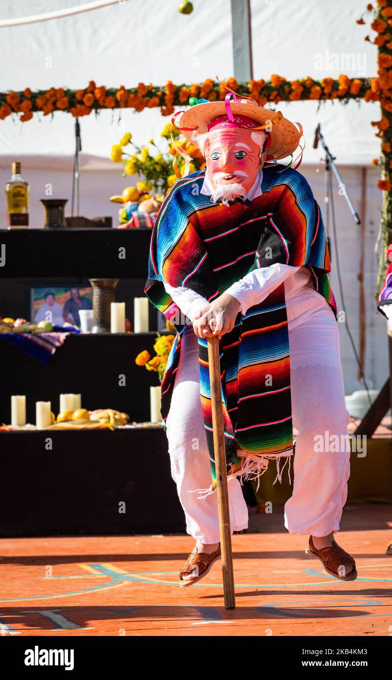 Eine kostümierte Tänzerin hüpft im Rahmen des humorvollen Viejitos-Tanzes (Tanz der Alten Männer), der während einer Dia de los Muertos-Veranstaltung aufgeführt wird, vom Boden. Stockfoto