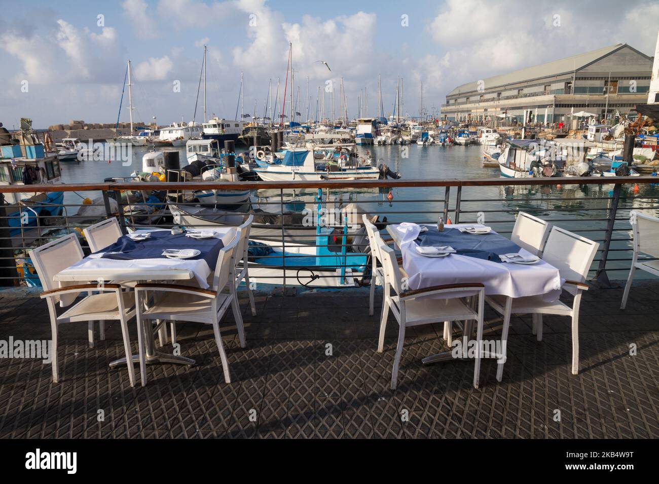 TEL AVIV, ISRAEL - 2. MÄRZ 2017 : Tische und Stühle in einem Restaurant in der Jaffa Hafenpromenade, vor Schiffen, die am Hafen ankern, Tel aviv, I Stockfoto