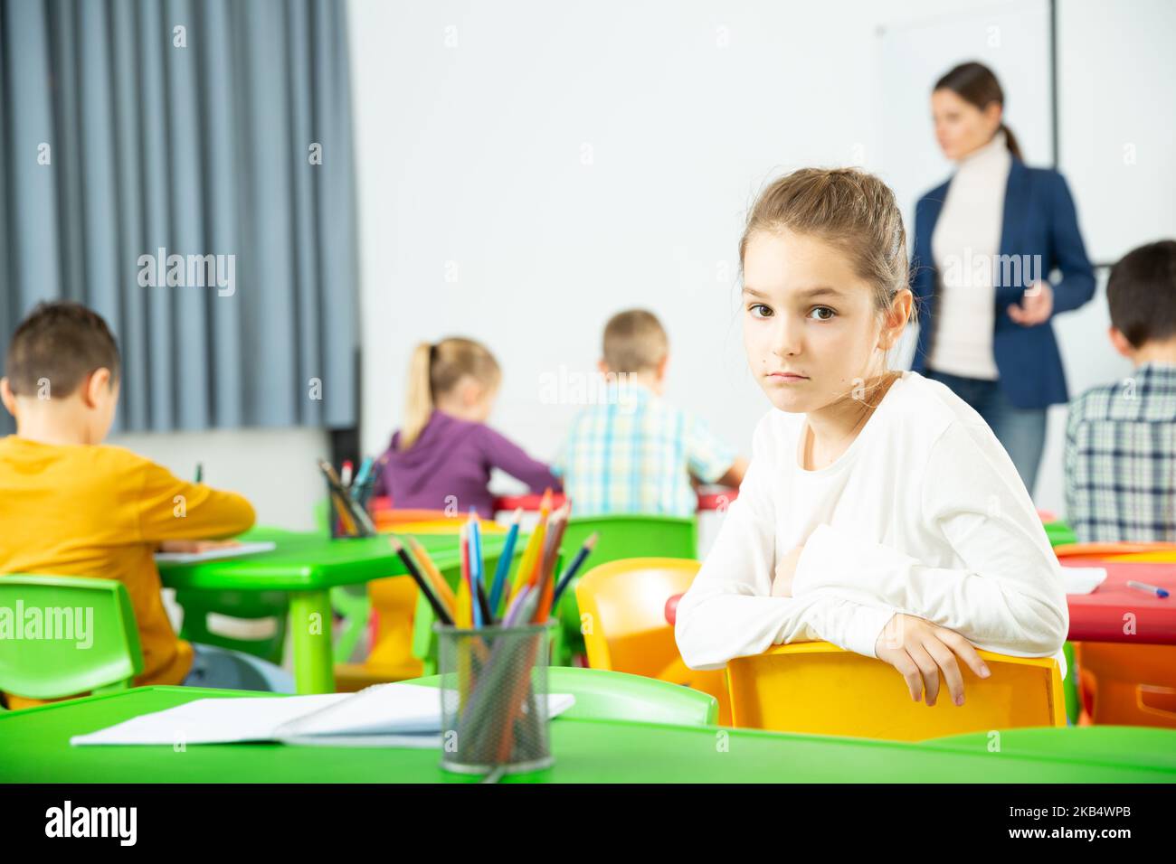 Verärgert Schulmädchen sitzt an einem Schreibtisch in Klassenzimmer Grundschule Stockfoto