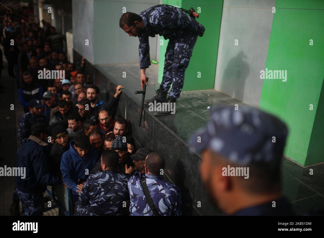 Sicherheitskräfte, die der Hamas treu sind, organisieren am 26. Januar 2019 Menschen, die sich vor dem zentralen Postamt in Gaza-Stadt anstellen, um finanzielle Hilfe von der katarischen Regierung für verarmte palästinensische Familien zu erhalten. (Foto von Majdi Fathi/NurPhoto) Stockfoto