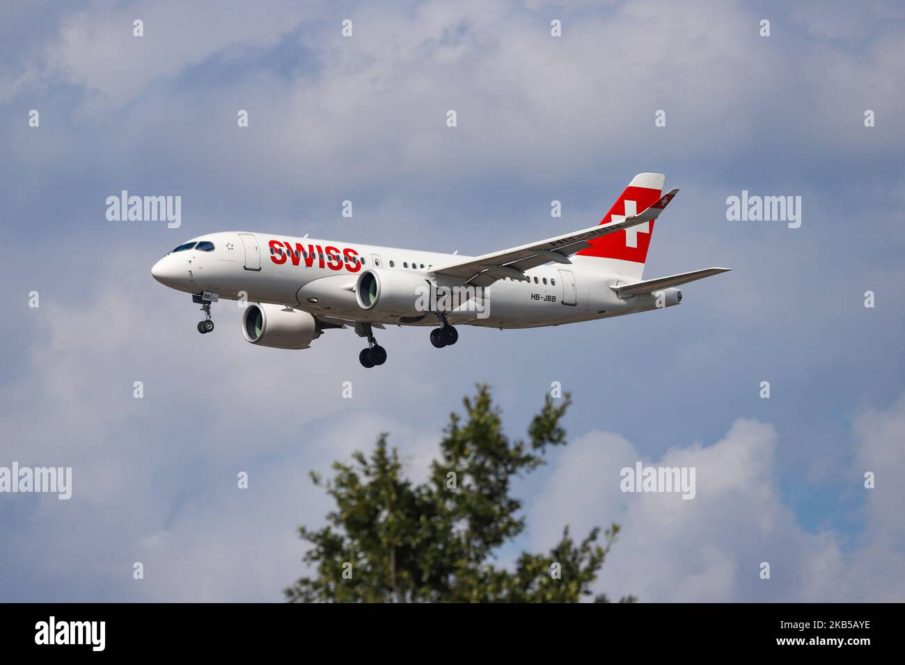 Swiss Airlines Bombardier BD-500 CSeries CS100 oder Airbus A220-100 wie bei der endgültigen Landung auf dem internationalen Flughafen London Heathrow LHR EGLL in England, Großbritannien, während eines bewölkten Sommertages gesehen. Das moderne Flugzeug hat die Zulassung HB-JBB, 2x Pratt & Whitney PW1524G Jet-Triebwerke und den Namen Canton de Genève. Swiss International Air Lines LX SWR ist die Schweizer Flaggengesellschaft, die sich im Besitz der Lufthansa Group befindet und Mitglied der Star Alliance Aviation Group ist. Die Fluggesellschaft war der weltweit einführende Kunde von Canadian Bombardier CS100/CS300, jetzt A220, die sowohl als regionale als auch als Mittelstreckenflüge durchgeführt wurden Stockfoto