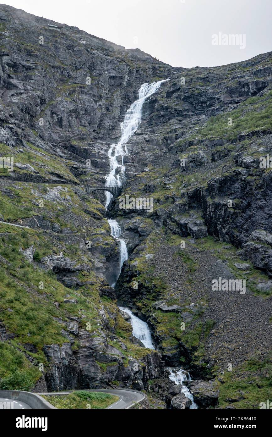 Berühmte Serpentine Scenic Mountain Road Trollstigen oder Trollstigveien, der Trollpfad, eine Bergstraße mit Wasserfällen in der Gemeinde Rauma, Bezirk More Og Romsdal, Norwegen. Die Route ist Teil der Norwegischen Kreisstraße 63, die Andalsnes mit Valldal und Geiranger Fjord verbindet, Trollstigen ist Teil der Norwegischen Panoramastraße Geiranger - Trollstigen. Die Straße ist nur während der Sommersaison geöffnet, sie ist schmal mit scharfen Kurven, aufsteigend 850 Meter, mit einem großen Wasserfall, Stigfossen von einer Höhe von 240 Metern und einer Brücke, Besucherzentrum für Touristen, Besucherplattform. Der Blick auf den Scandi Stockfoto