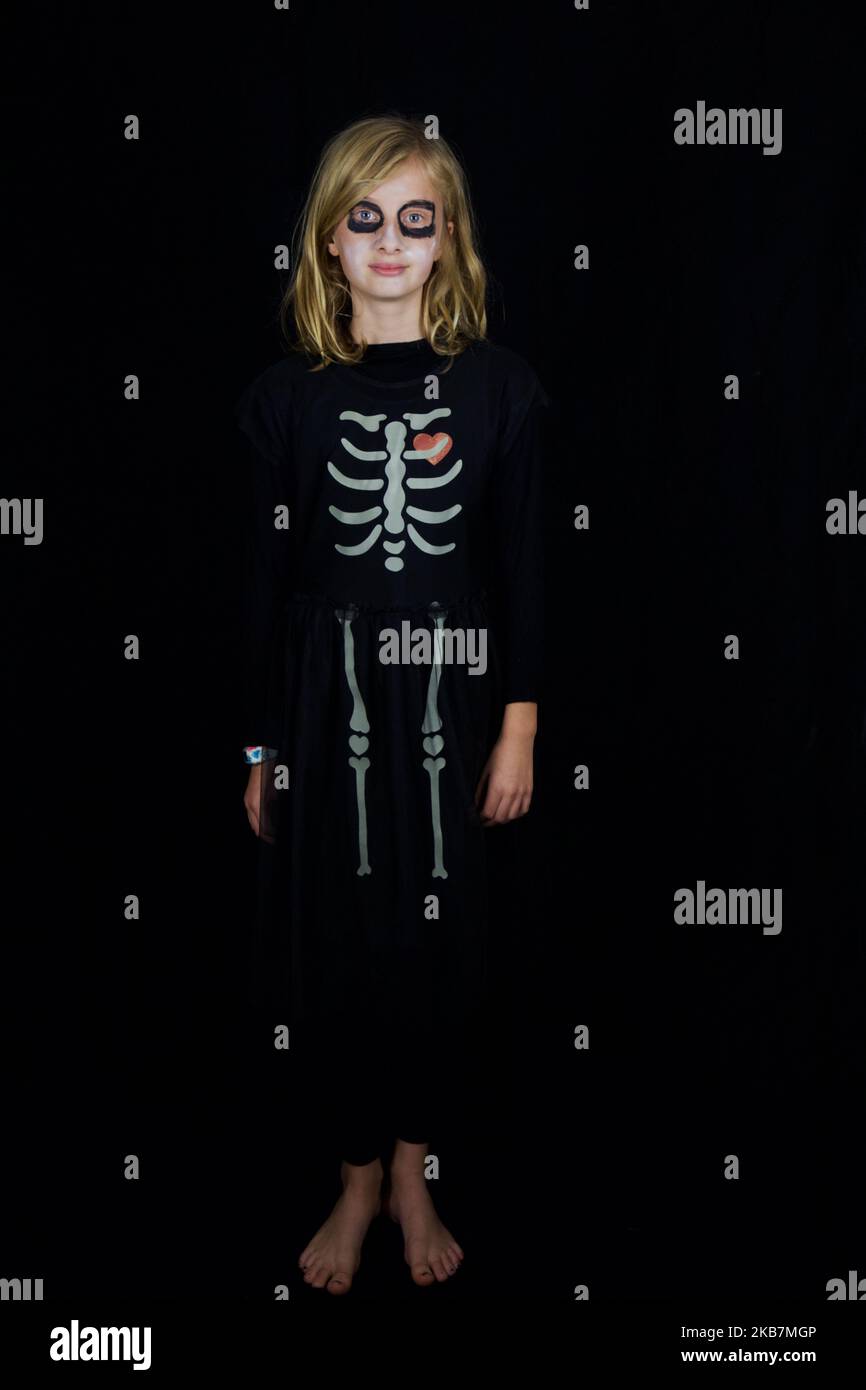 Ein Mädchen, das sich als Skelett verkleidet vor einem schwarzen Hintergrund Stockfoto