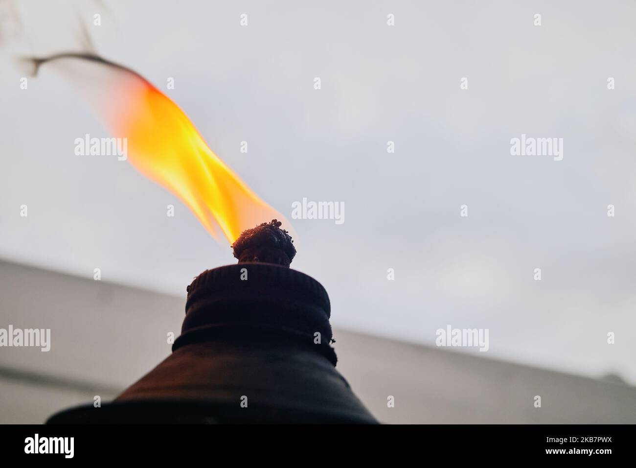 Flamme und brennender Docht auf einer Ölfackel vor einem bewölkten Himmel Stockfoto